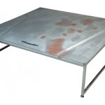 Three quarter view of an industrial table made with the hood of a Ford Thunderbird 1983 car.