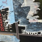 Detail of blue, black and red torn posters on an artwork made with two side doors of a GMC truck.